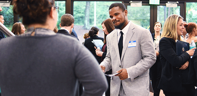 Students in suits and name tags talking during a gathering