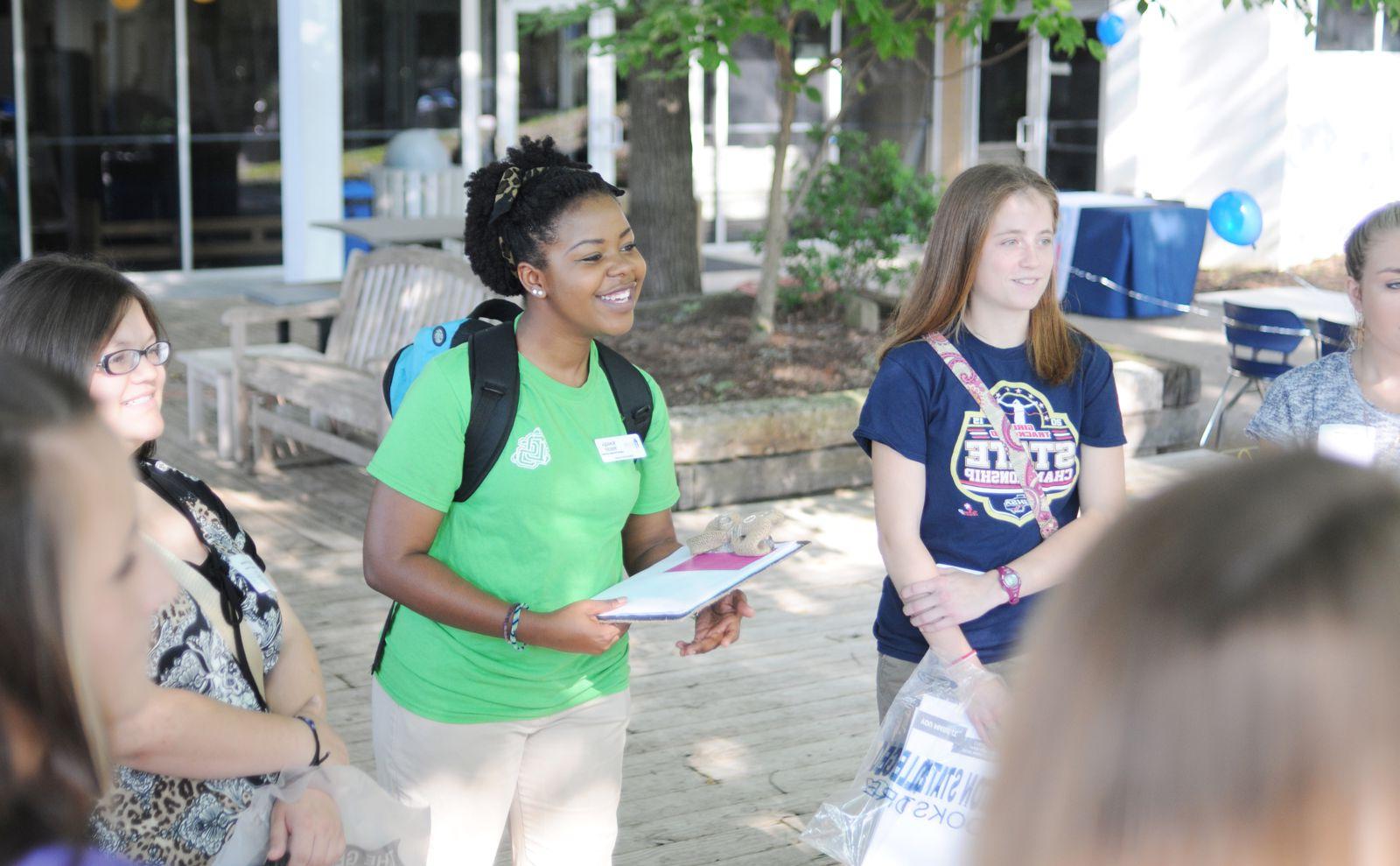 Student leader with clipboard listening to another student