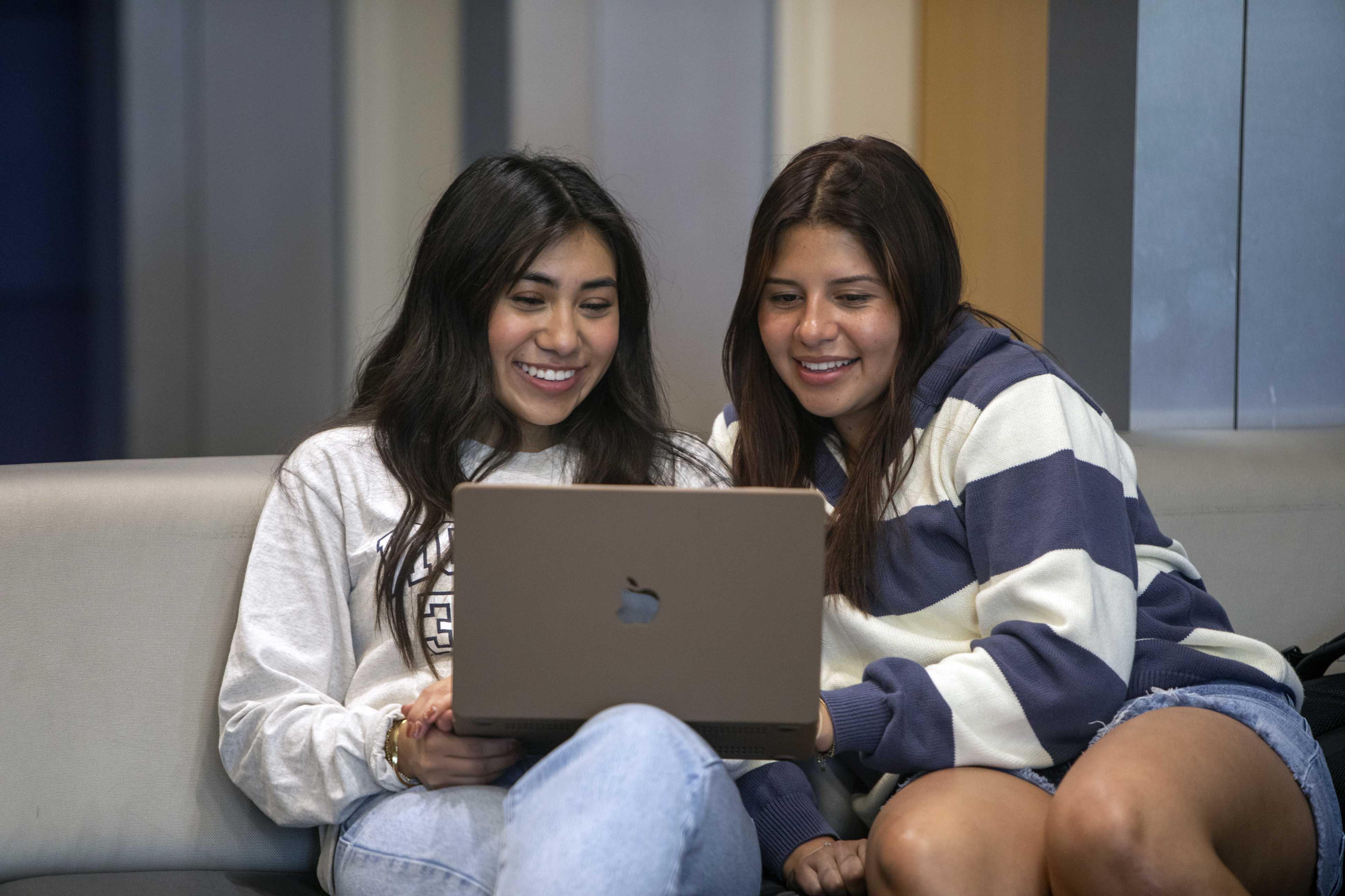 Two female students sharing a laptop, working