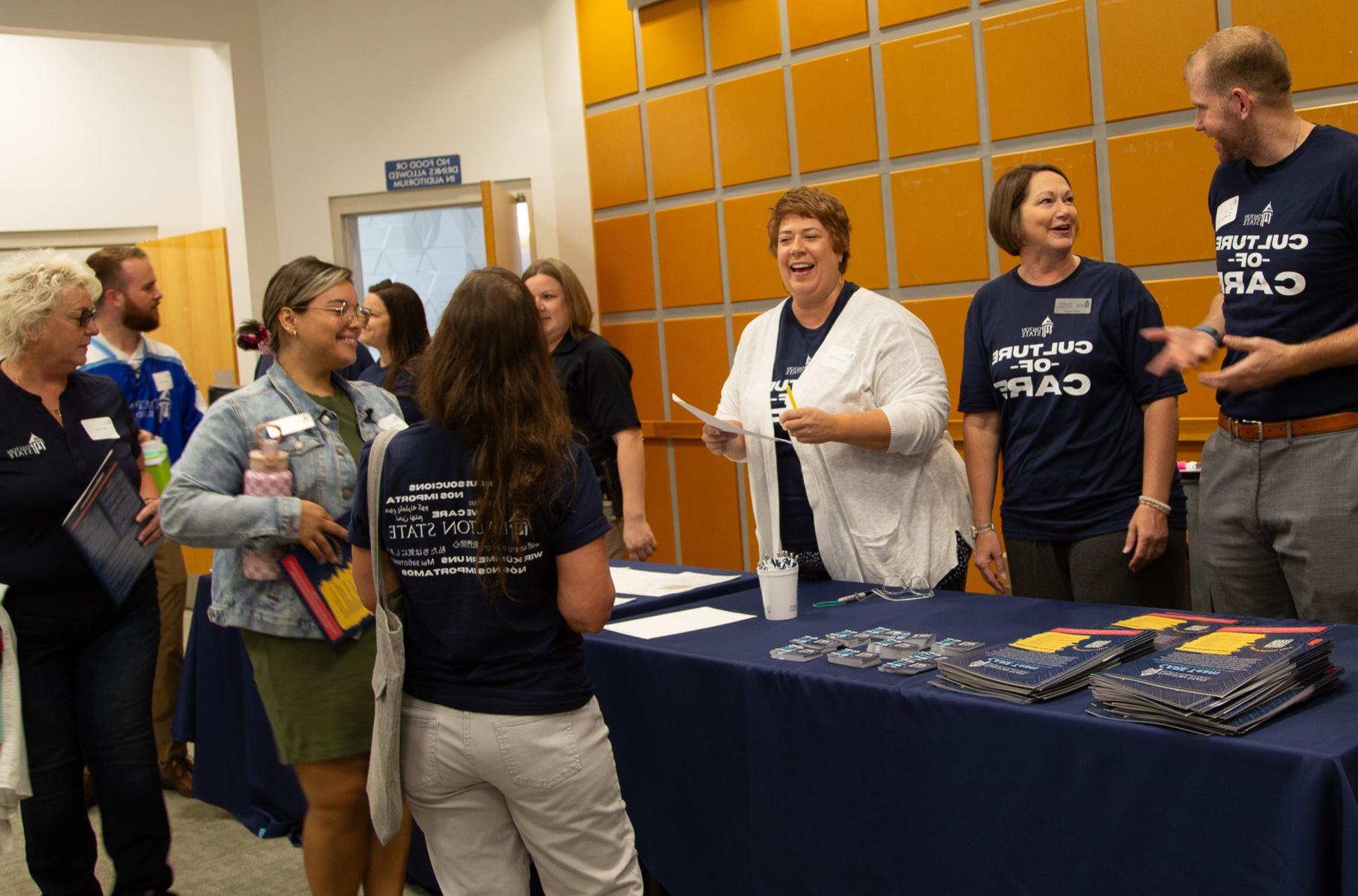 Smiling staff in Culture of Care t-shirts handing out materials to students